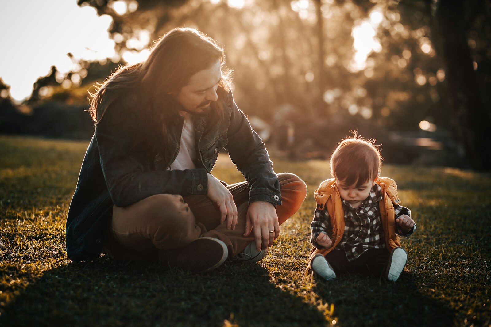 woman in black jacket sitting on ground beside girl in black jacket
