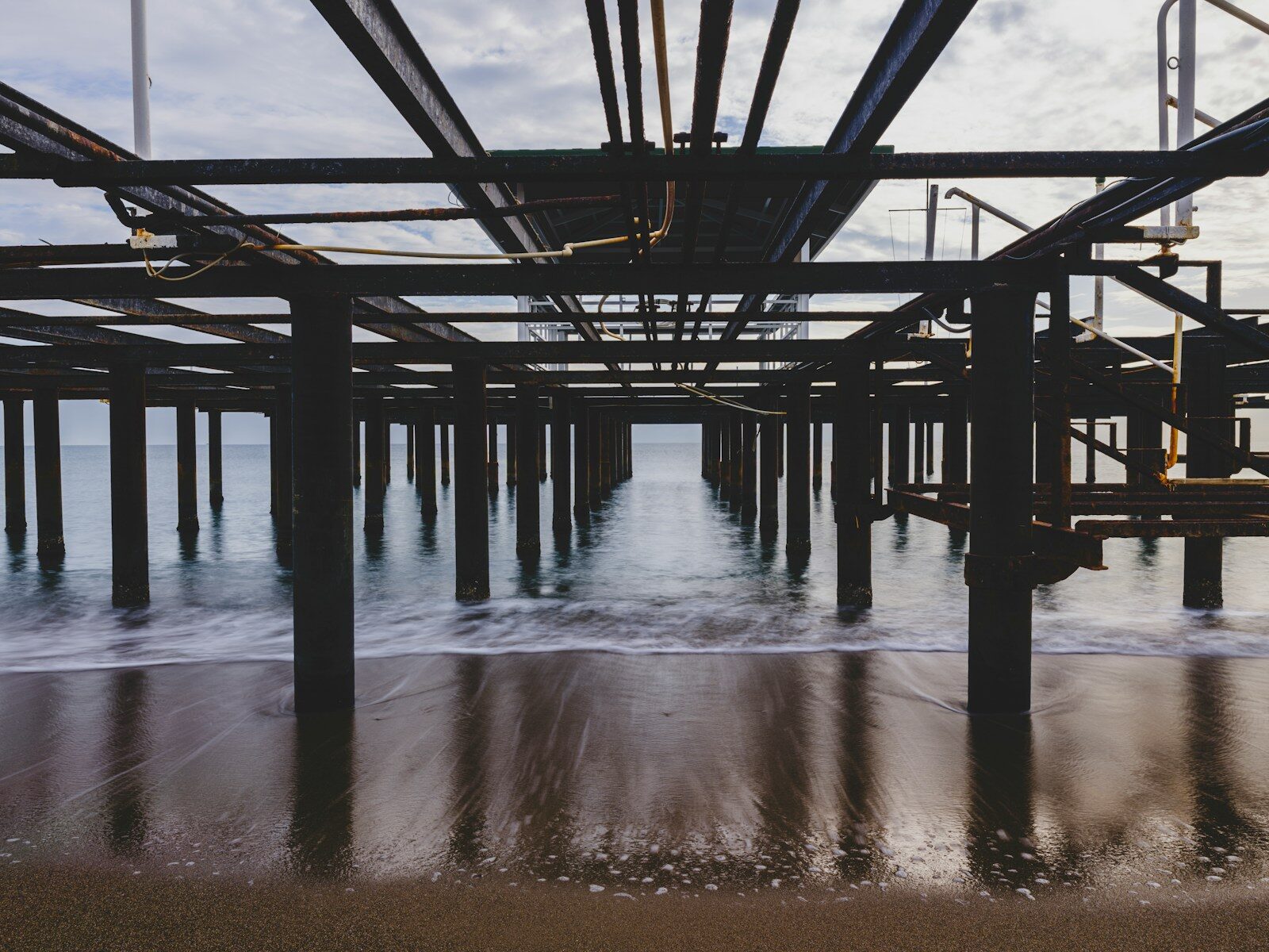 Underneath a pier with ocean waves and reflections